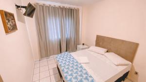 a bedroom with a bed with a blue and white blanket at Nacional Park Hotel Lages in Lages
