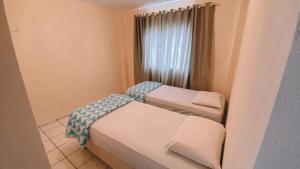 two beds in a small room with a window at Nacional Park Hotel Lages in Lages