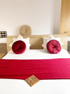 Bett mit roten und weißen Kissen und einer roten Decke in der Unterkunft Appart Aldyis in Sprimont