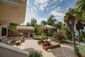 un patio con muebles, sombrilla y palmeras en ORRAON Lux Aparts K, en Preveza