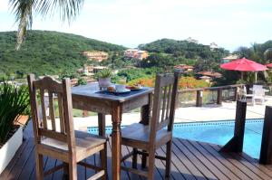 una mesa de madera y sillas en una terraza junto a la piscina en Ilha Branca Exclusive Hotel, en Búzios