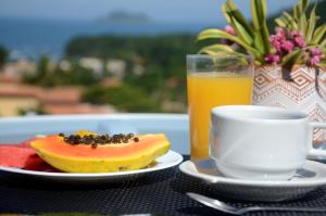 einen Tisch mit einem Obstteller und einer Tasse Orangensaft in der Unterkunft Ilha Branca Exclusive Hotel in Búzios