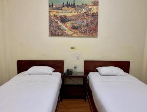 two beds sitting next to a desk in a room at Hotel Capri de Leon Mexico in León