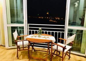 una mesa y sillas frente a una gran ventana en Tsarevets panoramic apartments Veliko Tarnovo, en Veliko Tŭrnovo