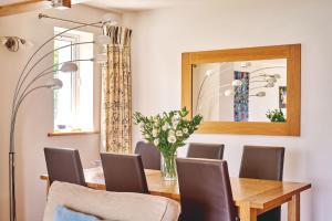 a dining room table with chairs and a vase of flowers at Seaview in Llandegfan