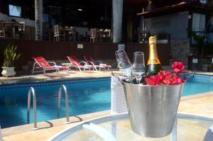 a bucket of champagne and flowers next to a swimming pool at Ilha Branca Exclusive Hotel in Búzios