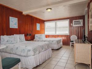 可可比奇的住宿－Sea Aire Oceanfront Inn，一间带两张床铺的卧室,位于带木墙的房间内
