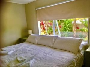 Bett in einem Zimmer mit einem großen Fenster in der Unterkunft Cozy Cottage in Whitianga