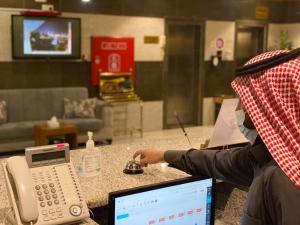 a person is sitting at a table with a telephone at فندق غالية احد in Al Madinah