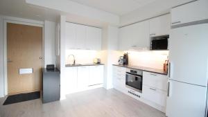 a kitchen with white cabinets and a refrigerator at New one bedroom apartment with TERRACE and Parking in Vantaa