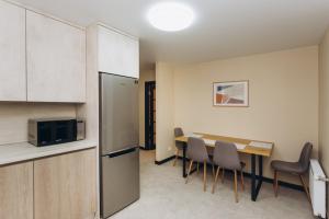 a kitchen with a table with chairs and a refrigerator at VIP Flat lavina проспект М Лушпи 2 корп2 in Sumy