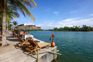 een groep tafels en stoelen op een steiger bij het water bij Flat Conchas e Corais - Village Paraíso localizado em Taipu de Fora, península de Barra Grande in Barra Grande