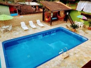 uma grande piscina com cadeiras e uma casa em Chalés Sonho Meu Com Cozinha em Visconde de Mauá