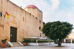 un bâtiment avec un arbre devant lui dans l'établissement LA NASSA SUITES & ROOMS, à Mazara del Vallo