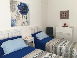 2 Betten in einem kleinen Zimmer mit blauer Bettwäsche in der Unterkunft Hibiscus in Taranto