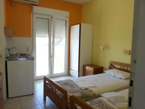 a bedroom with two beds and a kitchen with a sink at Elena Studios in Tarti