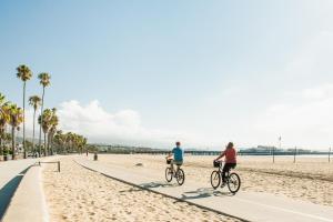 two people riding bicycles on a beach near the ocean at Lavender Inn by the Sea in Santa Barbara