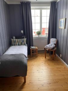 a bedroom with a bed and a chair and a window at Granavolden Gjæstgiveri in Gran