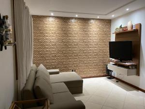 een woonkamer met een bank en een televisie bij Flat Conchas e Corais - Village Paraíso localizado em Taipu de Fora, península de Barra Grande in Barra Grande