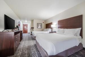 a hotel room with two beds and a flat screen tv at Cobblestone Hotel & Suites - Cozad in Cozad