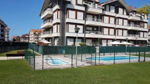 una valla frente a un edificio con piscina en Apartamento Turístico Los Altos en Noja