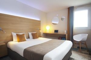 una camera d'albergo con un grande letto e una sedia di Kyriad Le Mans Est a Le Mans