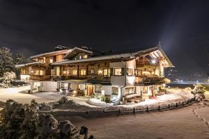 una imagen de una casa en la nieve por la noche en Aparthotel Stacherhof, en Fügen