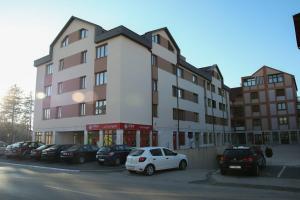 a large building with cars parked in a parking lot at Apartman "Park" in Livno