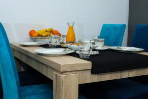 a wooden table with plates and glasses and a bowl of fruit at Apartman "Park" in Livno +14 photos