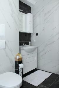 a white bathroom with a toilet and a sink at Apartman "Park" in Livno