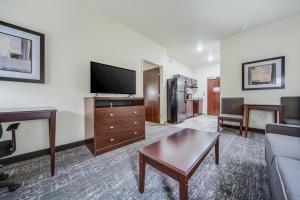 Cobblestone Hotel & Suites - Cozad في Cozad: غرفة معيشة مع أريكة وتلفزيون بشاشة مسطحة