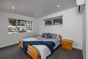 a bedroom with a bed and two windows at Waterfront Beach House - Paihia Holiday Home in Paihia
