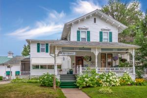 een wit huis met groene luiken bij Carriage House Bed & Breakfast in Winona