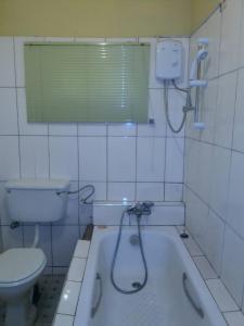 a bathroom with a bath tub and a toilet at Sampson's Guesthouse Company Ltd. in Kwashieman