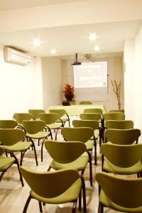 una sala de conferencias con sillas verdes y una pizarra en Hotel Palma 70 en Medellín
