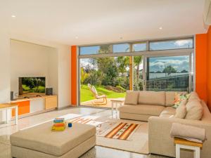 a living room with a couch and a tv at A Slice of Summer - Whangapoua Holiday Home in Whangapoua