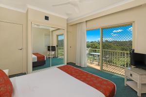Habitación de hotel con cama y balcón en Alex Seaside Resort, en Alexandra Headland