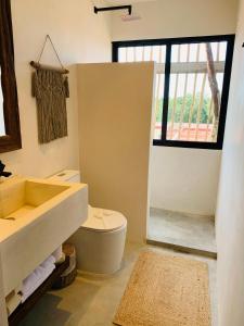a bathroom with a sink and a toilet and a window at Vida Jungle Boho Apart 13 with special fee to access Hotel Bardo in Tulum