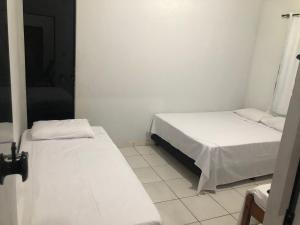 two beds in a small room with white walls at Pousada Ambiente Familiar in Ponte Alta do Tocantins