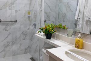 baño con lavabo y ducha con flores en Libertg Hotels Spa, en Copacabana