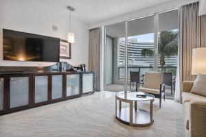 un soggiorno con una TV, un divano e un tavolo di Junior Suite at Sorrento Residences- FontaineBleau Miami Beach home a Miami Beach