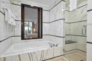 un bagno bianco con vasca e specchio di Junior Suite at Sorrento Residences- FontaineBleau Miami Beach home a Miami Beach