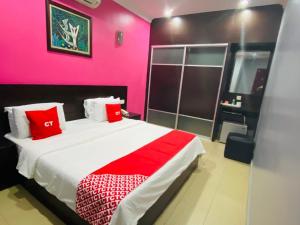 a pink bedroom with a bed with red pillows at Ct Hotel in Sitiawan