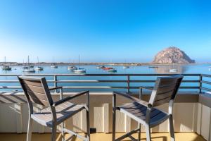 twee stoelen op een balkon met uitzicht op een haven bij Inn At Rose's Landing in Morro Bay