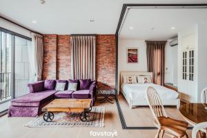 a living room with a purple couch and a bed at 23 Degrees Khao Yai by Favstay in Phayayen