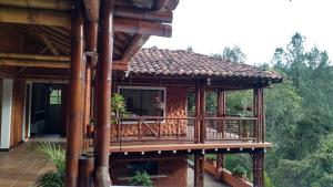 a wooden house with a deck in the woods at La Casona Del Retiro in Medellín