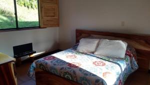 Dormitorio con cama con edredón y teclado en La Casona Del Retiro, en Medellín