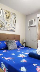 a bedroom with a bed with a blue comforter at One Oasis Apartment CDO in Cagayan de Oro