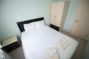 een slaapkamer met een groot wit bed en 2 slippers bij Liman Apart Hotel in Isparta