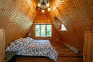 a bedroom with a bed in a wooden cabin at Chalet Vert le lac in Chertsey